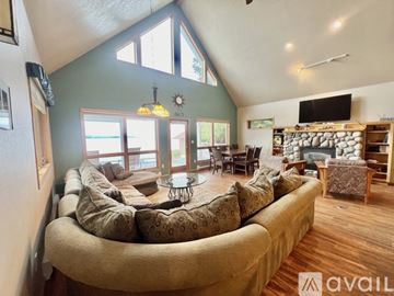 Polson house for rent - A living room with a large couch and a stone fireplace.