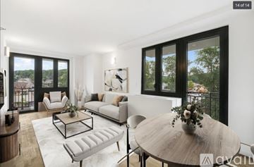 Peekskill apartment for rent - A modern living room with a white sofa, a coffee table, and a round table with a vase of flowers on it.