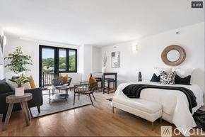 Peekskill apartment for rent - A modern bedroom with a large bed and a balcony with a view of the trees.