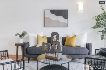 Peekskill apartment for rent - A grey couch with yellow and white pillows is the centerpiece of a modern living room.