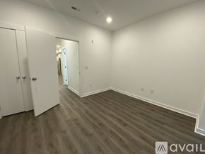 Philadelphia apartment for rent - A room with wooden flooring and white walls, with a door on the left and a mirror on the right.