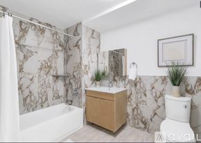 Peekskill apartment for rent - A bathroom with a marble patterned shower curtain and a wooden vanity.
