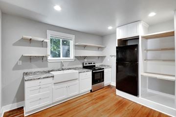 Spartanburg house for rent - A kitchen with white cabinets and a black refrigerator.