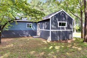 Spartanburg house for rent - A blue shed with a white window is surrounded by trees.