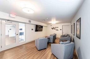 Arlington Heights apartment for rent - A waiting room with grey couches and a TV mounted on the wall.