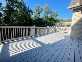 Louisville house for rent - A wooden deck with a white railing and trees in the background.