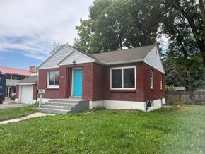 Provo house for rent - A red brick house with a blue door and a white garage door.