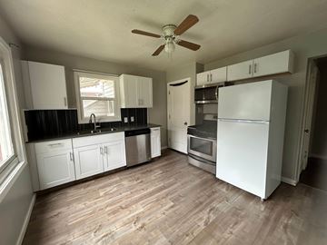 Provo house for rent - A kitchen with white cabinets and a wooden floor.