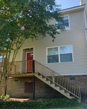 Hattiesburg house for rent - A house with a red door and a staircase leading to the entrance.