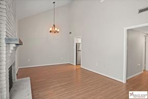 Hattiesburg house for rent - A large, empty room with wooden floors and a fireplace on the left side.