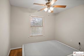 Hattiesburg house for rent - A bedroom with a ceiling fan and a window with blinds.