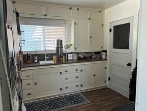 Payson house for rent - A kitchen with white cabinets and a black and white rug on the floor.