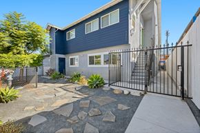 San Diego apartment for rent - A modern house with a blue exterior and a black metal fence.