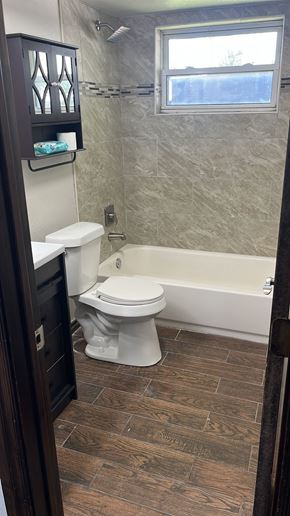 Oklahoma City house for rent - A bathroom with a toilet, a tub, and a window.