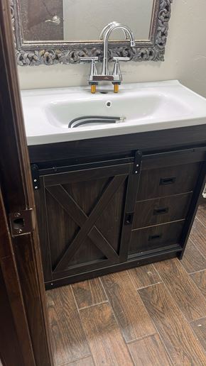 Oklahoma City house for rent - A bathroom sink with a wooden cabinet and a mirror above it.