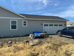 Kennewick house for rent - A blue car is parked in front of a grey house.