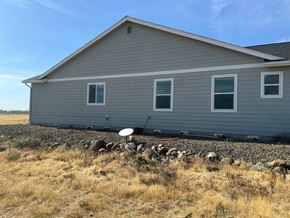 Kennewick house for rent - A house with a grey siding and a white window is surrounded by a rocky foundation.