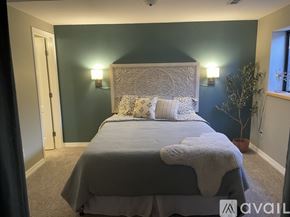 Colorado Springs apartment for rent - A bedroom with a bed in the center and a wall sconce on the wall.