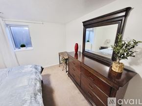 Idaho Falls apartment for rent - A bedroom with a large bed, a mirror, and a chair.