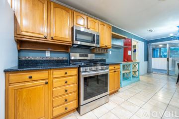 Gainesville house for rent - A kitchen with wooden cabinets and a black countertop.