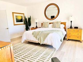Palm Desert house for rent - A bedroom with a bed, nightstand, and a painting on the wall.
