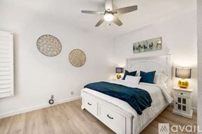 Palm Desert house for rent - A bedroom with a white bed and a ceiling fan.