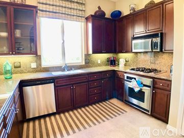 La Quinta house for rent - A kitchen with wooden cabinets and a stainless steel dishwasher.