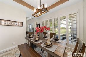 La Quinta house for rent - A dining room with a wooden table and chairs, a hanging light fixture, and a "HOME" sign on the wall.