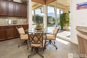 La Quinta house for rent - A kitchen with brown chairs and a glass table.