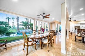 La Quinta house for rent - A dining room with a table set for six with a view of a pool and palm trees.