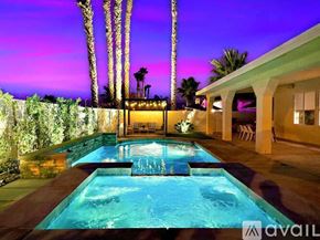 Indio house for rent - A pool surrounded by a stone wall and palm trees.