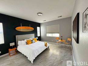 Indio house for rent - A bedroom with a large bed and a surfboard on the wall.