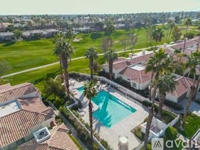 La Quinta house for rent - A large house with a pool surrounded by palm trees.