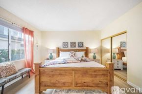 La Quinta house for rent - A bedroom with a wooden bed and a bench by the window.