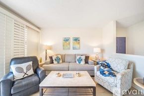 La Quinta house for rent - A living room with a grey leather chair, a white patterned couch, and a coffee table.