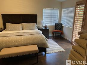 La Quinta house for rent - A bedroom with a large bed and a chair with a red cushion.