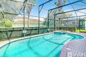 Kissimmee house for rent - A pool enclosed by a fence with trees in the background.