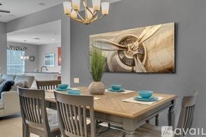 Kissimmee house for rent - A dining room with a wooden table and chairs, a chandelier, and a large painting on the wall.