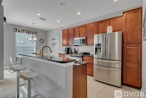 Kissimmee house for rent - A kitchen with wooden cabinets and a stainless steel refrigerator.