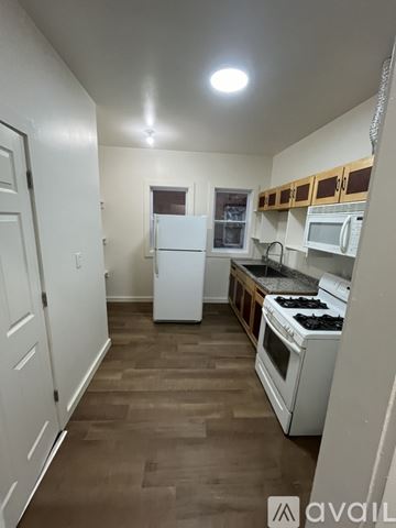 Detroit house for rent - A kitchen with white appliances and wooden floors.
