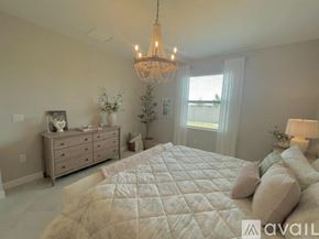 Port Charlotte house for rent - A bedroom with a large bed, a chandelier, and a dresser with a mirror.