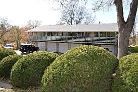 Lakewood apartment for rent - A green bush is in front of a building.