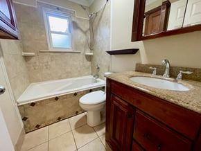 Oldham house for rent - A bathroom with a white toilet, a bathtub, and a sink.