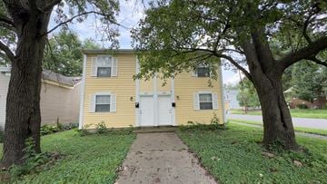 Jeffersonville house for rent - A yellow house with a white door and windows is surrounded by trees.