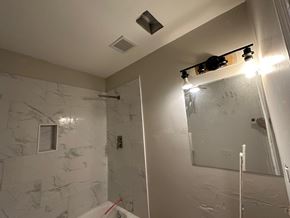 Atlanta house for rent - A bathroom with a marble wall and a glass shower door.