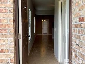 Siloam Springs townhouse for rent - A hallway with a brick wall on the left and a white door on the right.