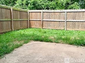 Siloam Springs townhouse for rent - A wooden fence encloses a grassy area with a dirt path leading to it.