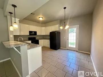 Siloam Springs townhouse for rent - A kitchen with a black refrigerator and white cabinets.