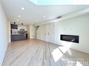Chicago condo for rent - A spacious room with wooden flooring and white walls.