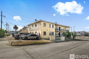 Los Angeles apartment for rent - A beige building with a balcony and a tree in front.